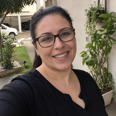 Selfie de Juliana, síndica, de óculos e blusa preta na área comum do condomínio